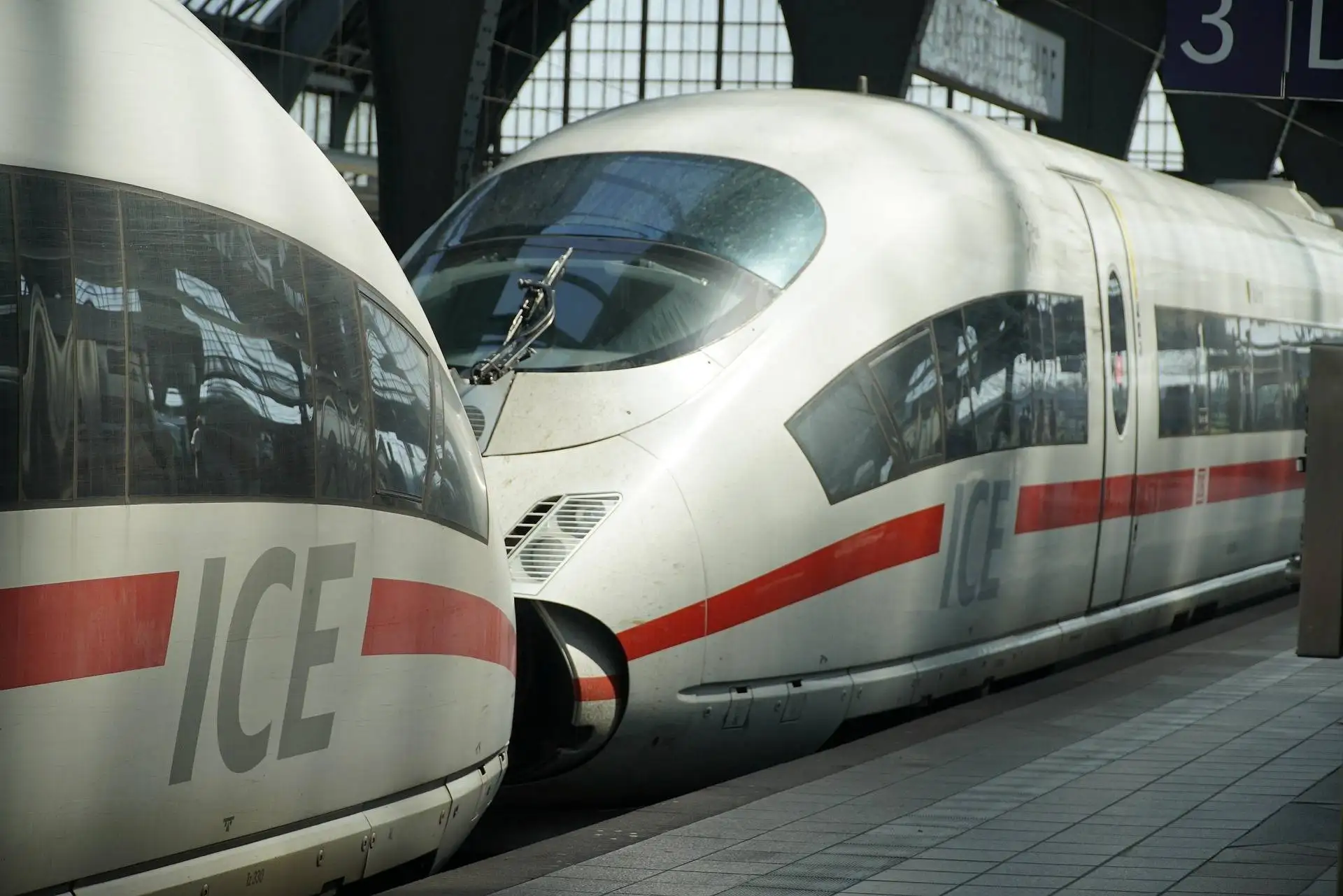 High-speed ICE train at a platform with a white body and red stripe along the side.